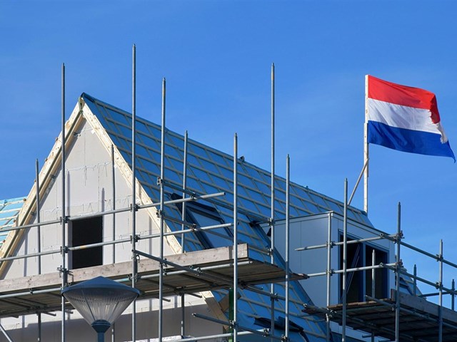 Dak van huis in aanbouw met Nederlandse vlag